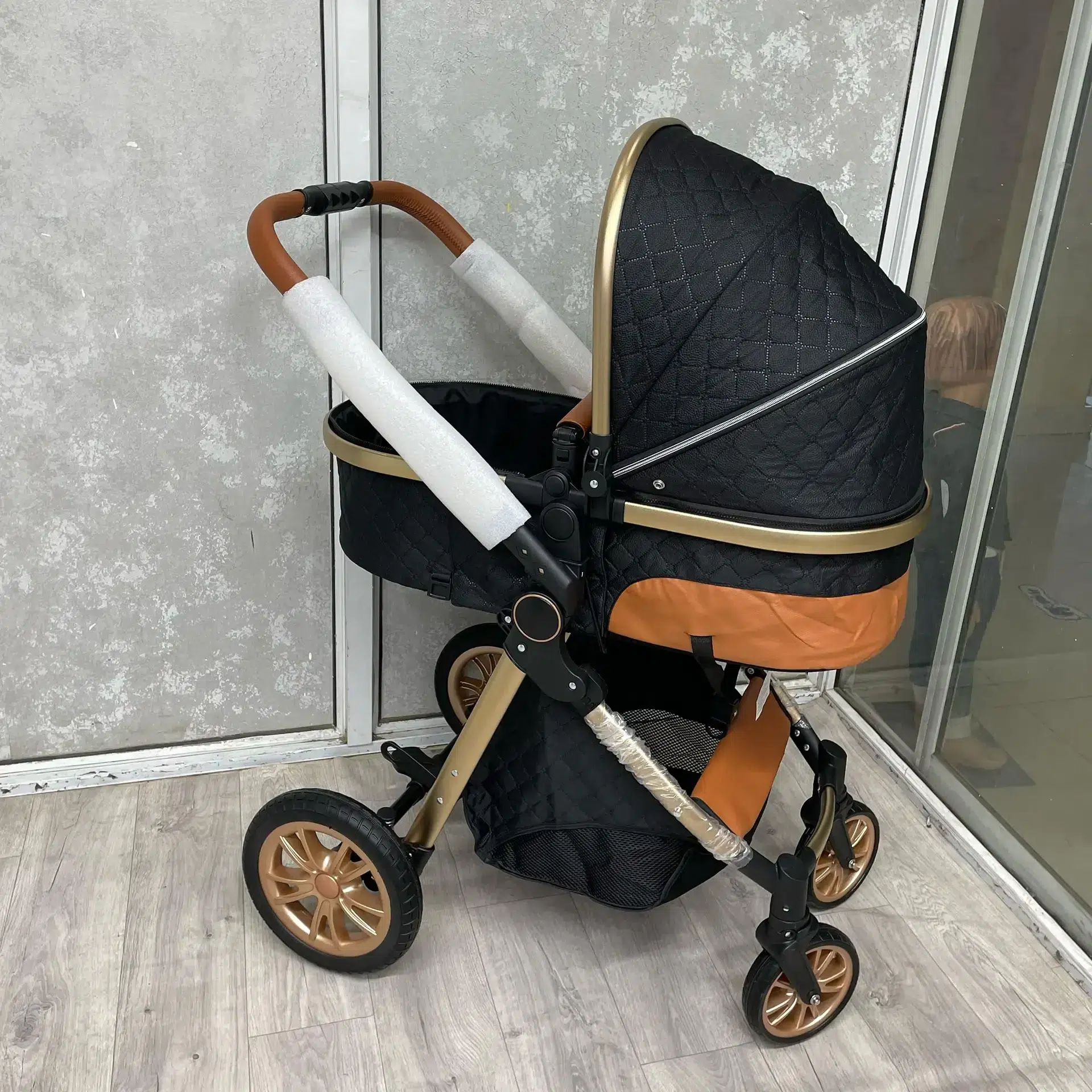 A stylish 3-in-1 premium baby stroller in black and gold, featuring a quilted design, adjustable handlebar, and durable wheels. Includes a detachable infant car seat for versatile use. Perfect for comfort, safety, and convenience.