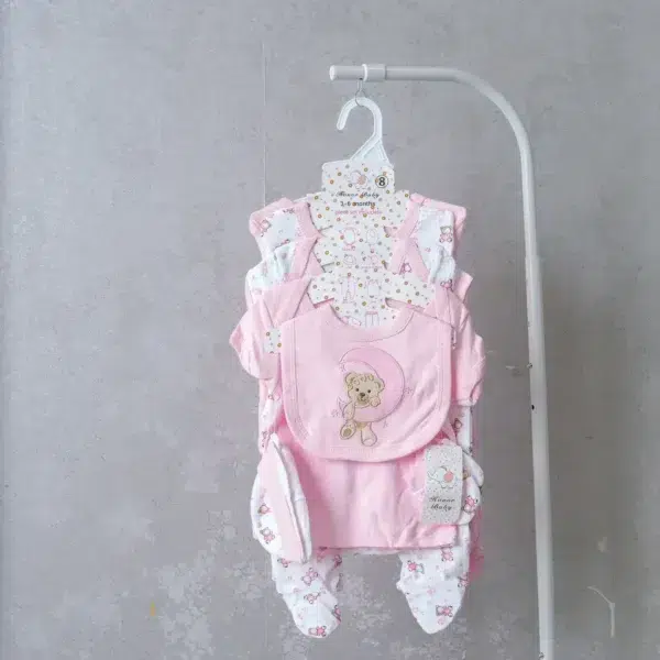 8-piece baby girl receiving set in soft pink with teddy bear embroidery, including bodysuit, bib, mittens, and footed pants.
