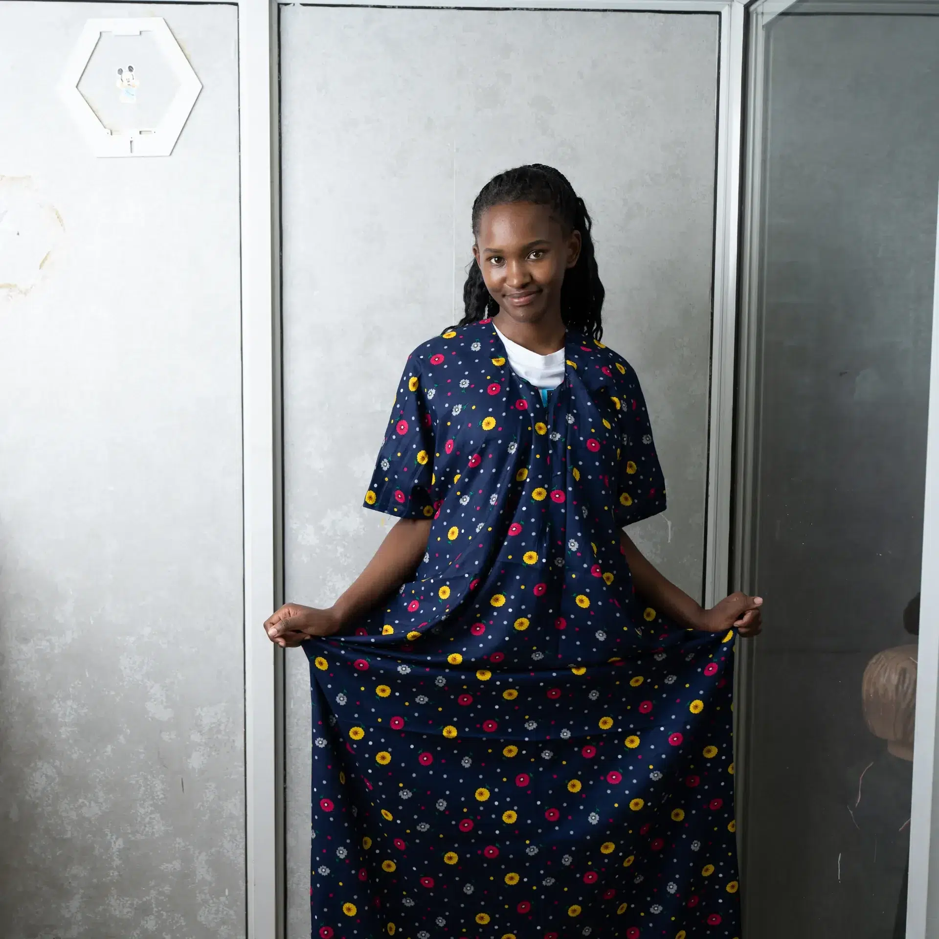 Woman modeling a navy blue nursing dera featuring a colorful floral print, highlighting the garment’s modest coverage and relaxed fit.
