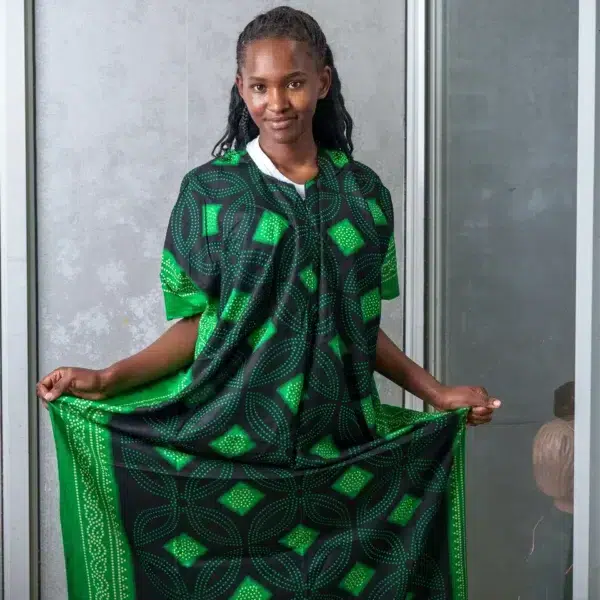 Woman dressed in a black nursing dera with green African-inspired patterns, smiling and displaying the wide, flowing cut of the outfit.