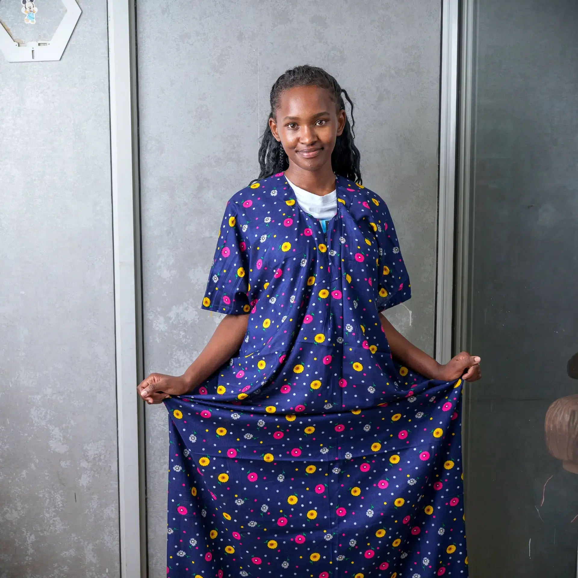 Woman modeling a navy blue nursing dera featuring a colorful floral print, highlighting the garment’s modest coverage and relaxed fit.